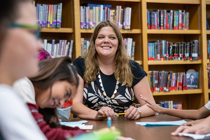 A woman smiles at a table with her students