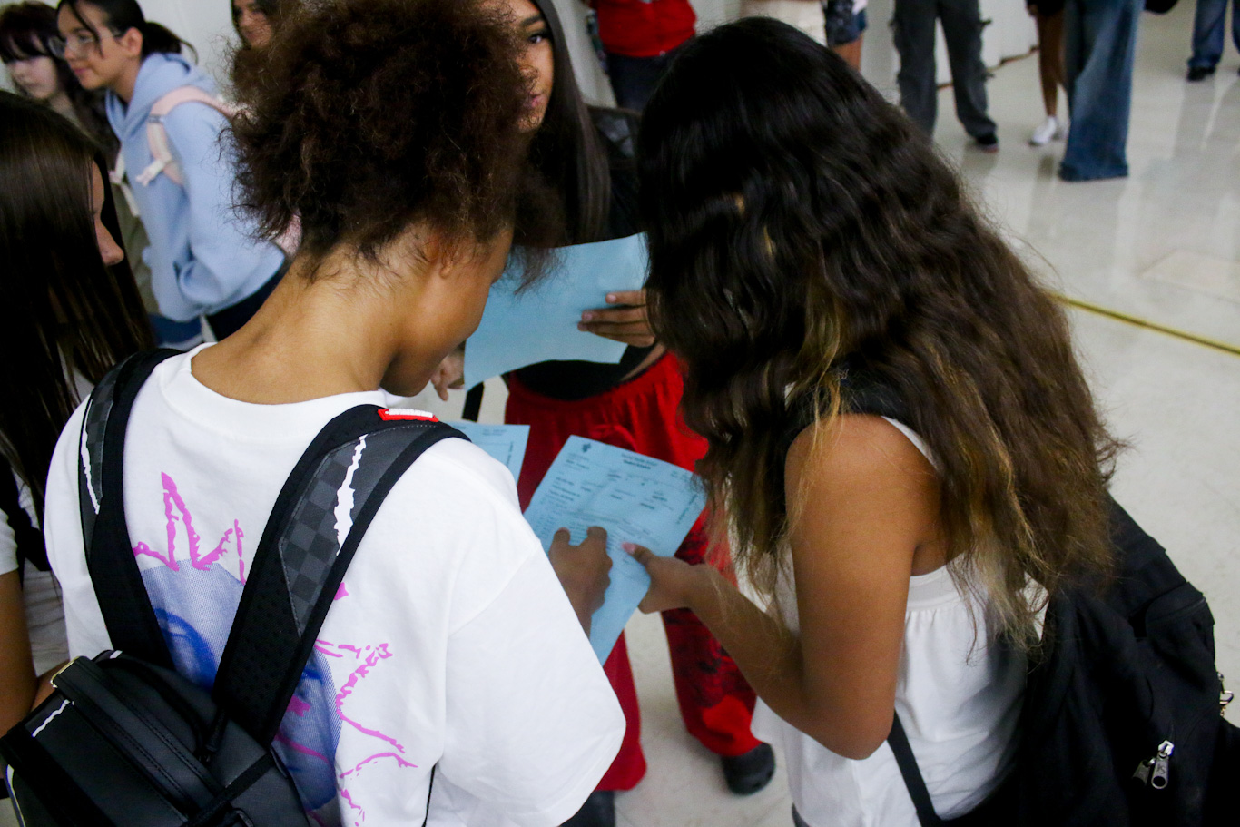 A group of preteen girls look over their class schedules in the hallway